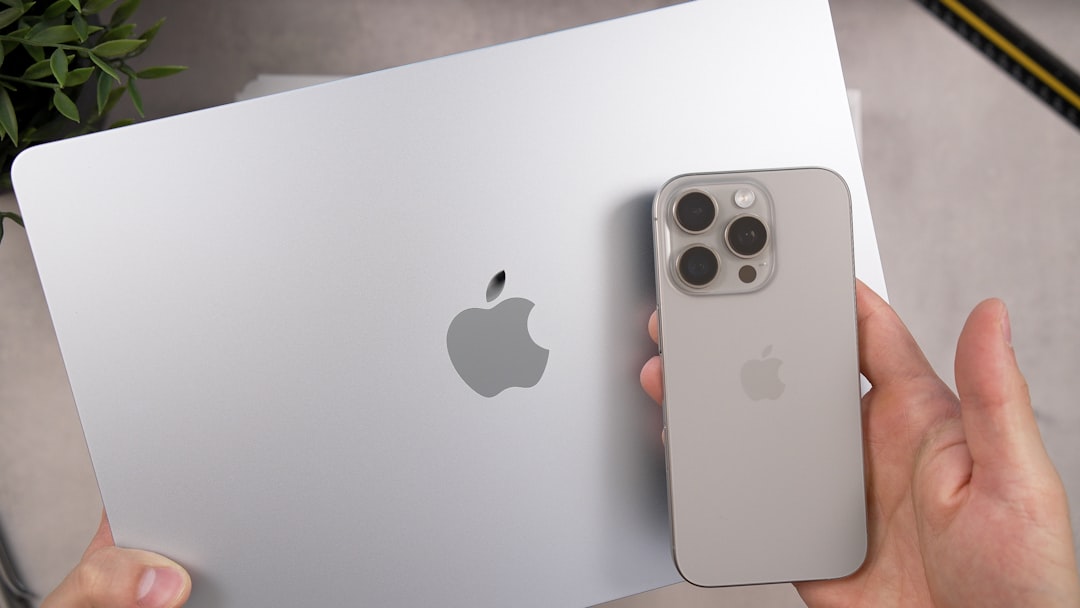 Silver apple laptop and iPhone held by hands